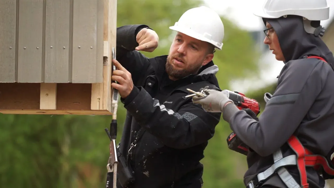 SSR Monteure befestigen ein vorgefertigtes Holzrahmen-Fassadenelement